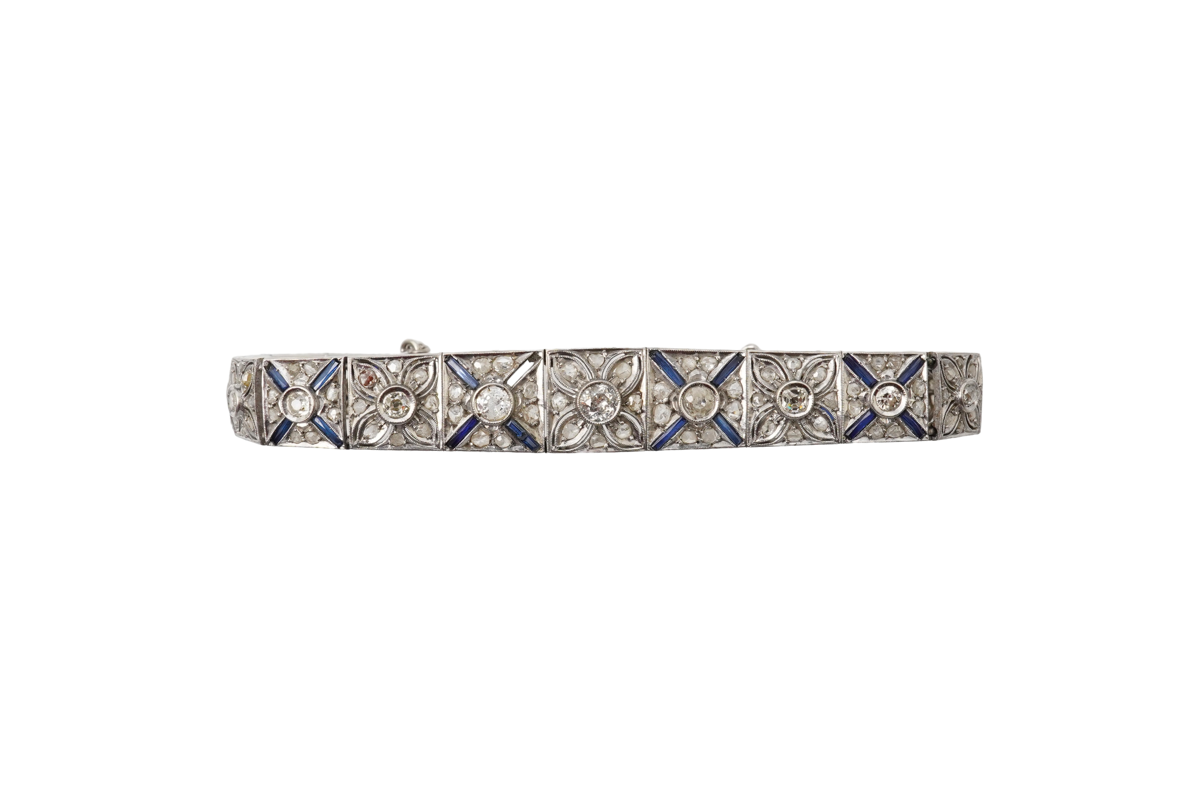 An Art Deco diamond and synthetic sapphire bracelet, 1920s, composed of tapering square panel links of openwork floral design, set with circular-cut and rose-cut diamonds, crossed with calibré-cut synthetic sapphires, mo